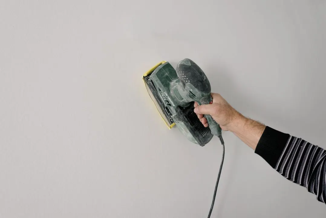Interior wall being sanded smooth before primer and paint