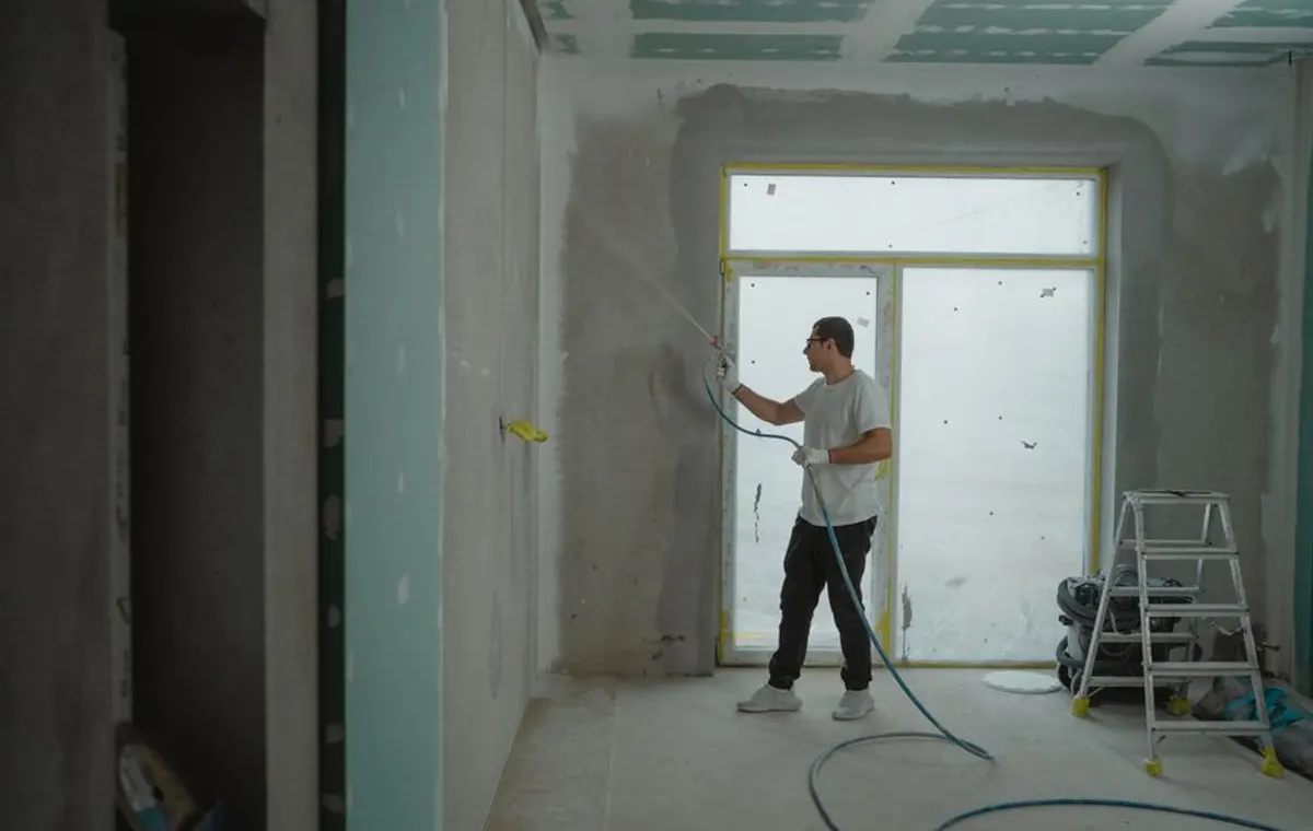 Painter spraying and preparing an interior room for a repaint