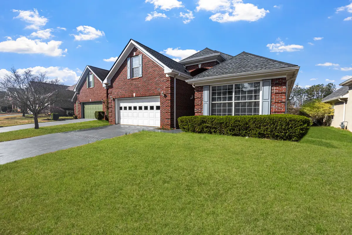Natural red brick suburban home with white trim and a green lawn