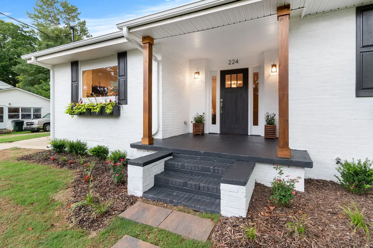 White painted brick house with black accents and natural wood porch posts