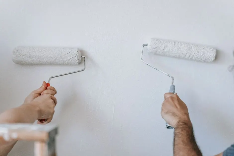 Two people rolling paint on an interior wall during a home painting project