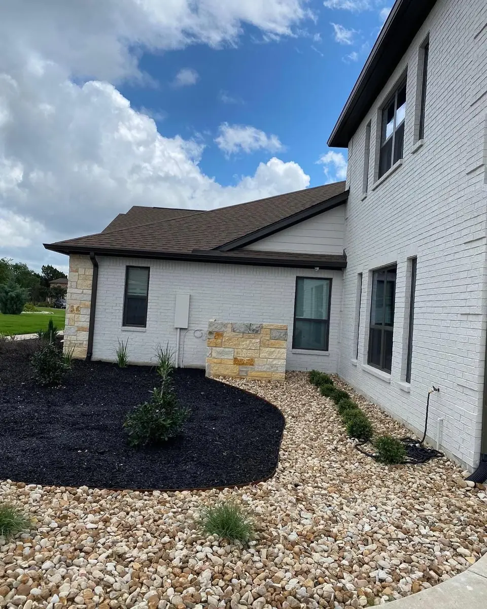White brick residential exterior with black landscaping mulch painted by New Life Painting