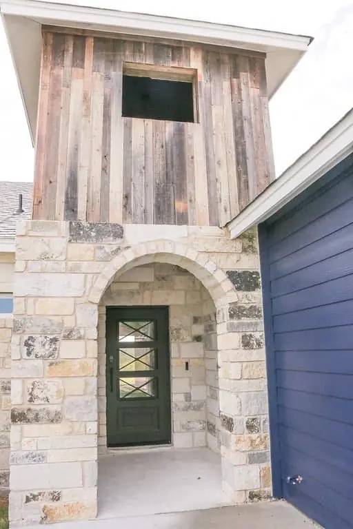 New construction exterior entry with painted garage door and trim details