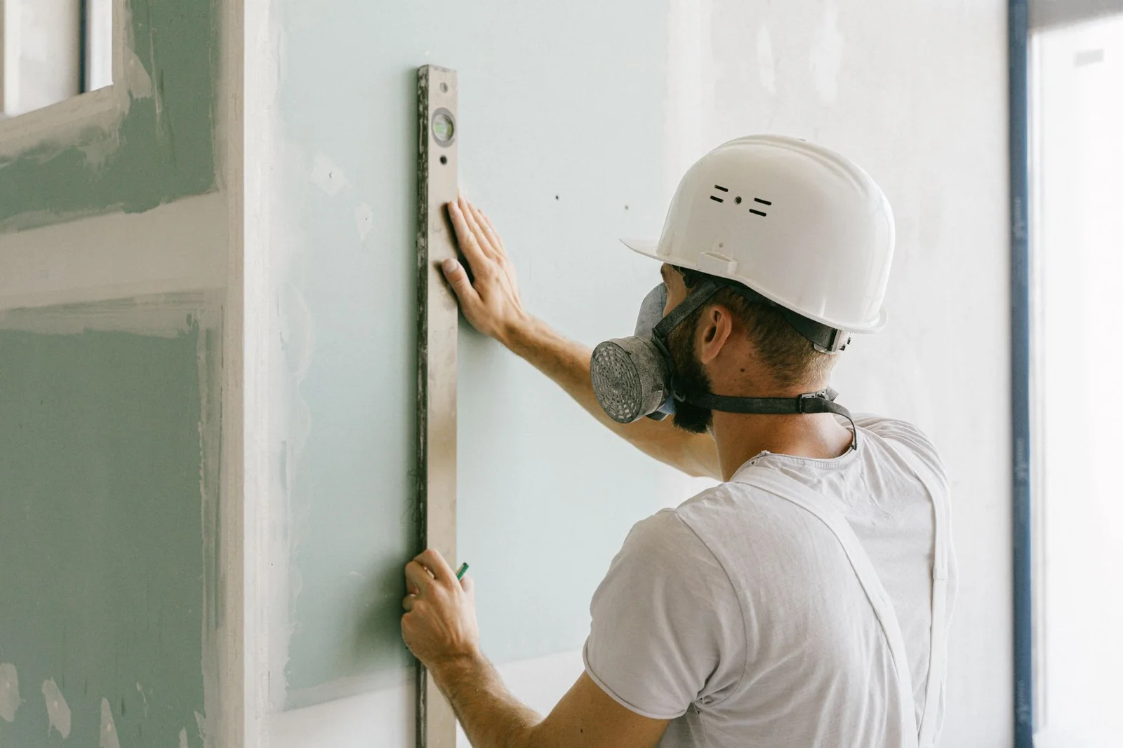 Drywall professional checking a newly finished wall for a smooth, paint-ready surface
