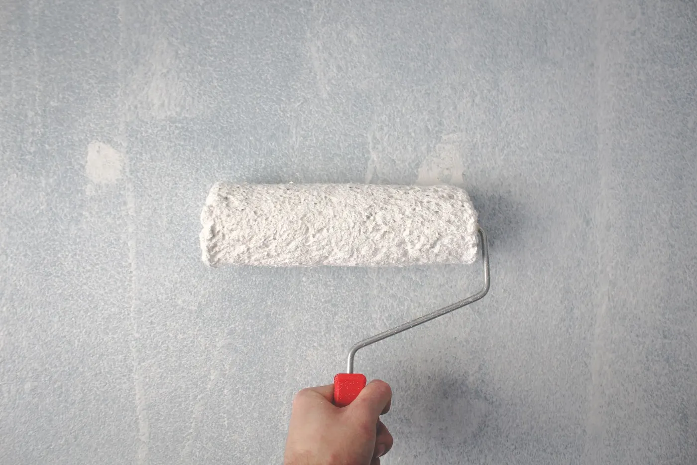 Paint roller applying a clean white finish to an interior wall